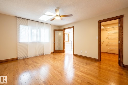 Hardwood flooring complemented by a ceiling fan with integrated lighting, a skylight, and paneled window coverings - 4632 151 Street, Edmonton, AB - Indoor Photo Showing Other Room