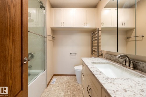 Bathroom featuring a vanity with an integrated sink, a speckled countertop, and brushed nickel fixtures - 4632 151 Street, Edmonton, AB - Indoor Photo Showing Bathroom
