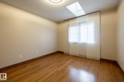 Room featuring wood-finish flooring, a skylight, and a window with blinds and sheer panel coverings - 