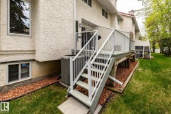 Rear exterior featuring a multi-level deck with white railings, a concrete patio, and a manicured lawn - 