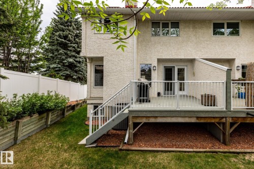 Rear exterior featuring a multi-level deck with white railings, a stucco finish facade, and mature perimeter trees - 4632 151 Street, Edmonton, AB - Outdoor With Deck Patio Veranda
