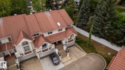 Multi-level townhome exterior featuring an orange tile roof, white facade, and integrated garage - 