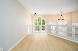 Open loft area featuring wood-finish flooring, light neutral wall colors, and a white spindle railing - 