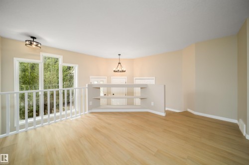 Expansive loft area featuring light wood-finish flooring, a white railing, and a built-in shelving unit - 1212 Ormsby Lane, Edmonton, AB - Indoor