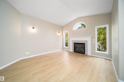 Vaulted ceiling living space featuring light wood-finish flooring, a fireplace with decorative tile surround, and multiple windows including an arched transom - 