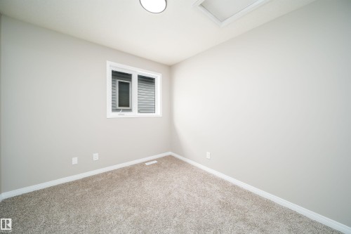 Carpeted room featuring a double-pane window, neutral wall paint, white trim, and a flush-mount ceiling light - 1212 Ormsby Lane, Edmonton, AB - Indoor Photo Showing Other Room