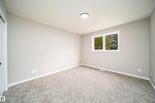 Carpeted room with a double-pane window, flush-mount ceiling light, white baseboards, and a paneled white door with dark hardware - 1212 Ormsby Lane, Edmonton, AB - Indoor Photo Showing Other Room