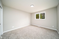 Carpeted room with a double-pane window, flush-mount ceiling light, white baseboards, and a paneled white door with dark hardware - 