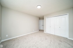 Spacious room featuring light-colored carpeting, neutral wall tones, white baseboards, and a large bi-fold closet with panel doors - 