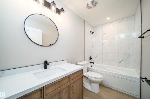 Bathroom featuring a wood-finish vanity with an integrated sink, a white countertop, and a matte black faucet - 1212 Ormsby Lane, Edmonton, AB - Indoor Photo Showing Bathroom