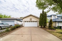 Attached garage with white panel door and upper window-style accents, featuring light-toned horizontal siding - 