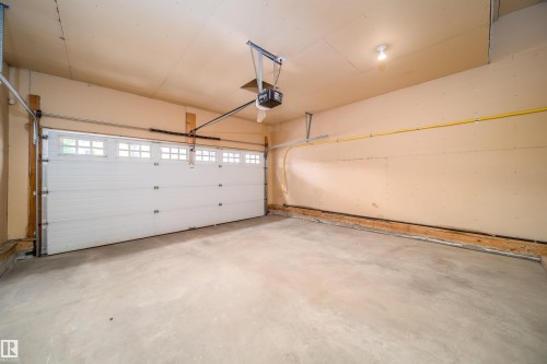 Integrated garage space featuring a paneled overhead door with upper window inserts, an automatic door opener, and concrete flooring - 1212 Ormsby Lane, Edmonton, AB - Indoor Photo Showing Garage