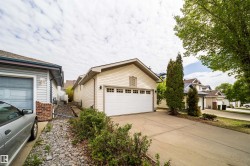 Exterior featuring light-colored siding, a white garage door with window inserts, and a concrete driveway - 