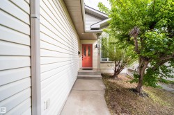 Inviting front entrance featuring a vibrant red door, concrete walkway, and white siding - 