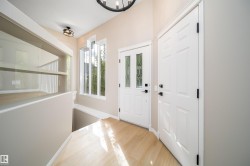 Foyer featuring wood-finish flooring, a white paneled entry door with decorative glass inserts, and a coordinating white interior door with black hardware - 