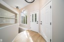Foyer featuring wood-finish flooring, a white paneled entry door with decorative glass inserts, and a coordinating white interior door with black hardware - 1212 Ormsby Lane, Edmonton, AB  - Indoor Photo Showing Other Room 