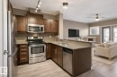 Kitchen featuring wood-finish cabinetry, stainless steel appliances, and a double basin sink - 334 10121 80 Avenue, Edmonton, AB  - Indoor Photo Showing Kitchen With Stainless Steel Kitchen With Double Sink 