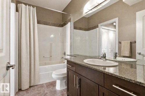 Bathroom featuring a dark wood-finish vanity with a granite-style countertop, an oval undermount sink, and a large wall-mounted mirror - 334 10121 80 Avenue, Edmonton, AB - Indoor Photo Showing Bathroom