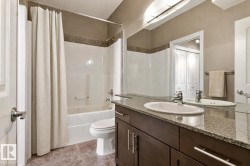 Bathroom featuring a dark wood-finish vanity with a granite-style countertop, an oval undermount sink, and a large wall-mounted mirror - 
