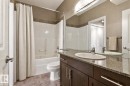 Bathroom featuring a dark wood-finish vanity with a granite-style countertop, an oval undermount sink, and a large wall-mounted mirror - 334 10121 80 Avenue, Edmonton, AB  - Indoor Photo Showing Bathroom 