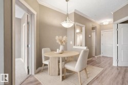 Dining area featuring wood-finish flooring, crown molding, and a contemporary pendant light fixture - 