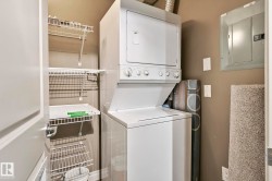 Dedicated laundry area featuring a stacked white washer and dryer unit, wire shelving, a light brown wall color, and a visible electrical panel - 