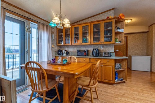 Kitchen area featuring warm wood-finish cabinetry with glass-front uppers, a light-toned countertop, and wood-finish flooring - 1529 Range Road 272 Rural Parkland County, Alberta, Rural Parkland County, AB - Indoor Photo Showing Dining Room
