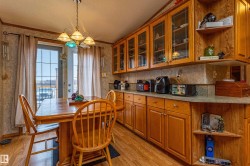 Warm kitchen and dining area featuring wood-finish flooring, a patio door, and a built-in cabinetry system - 