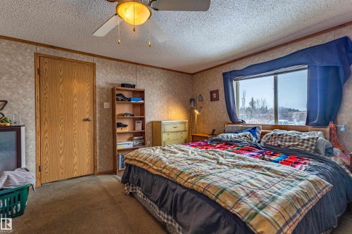 Bedroom featuring textured wall panels with wood trim accents, a large window, and carpet flooring - 1529 Range Road 272 Rural Parkland County, Alberta, Rural Parkland County, AB - Indoor Photo Showing Bedroom