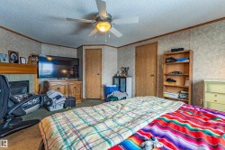Interior space featuring a ceiling fan with integrated lighting, wood-finish doors, textured wall paneling, and a built-in fireplace with a wood mantle - 