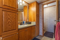 Bathroom featuring ample wood-finish cabinetry, a single basin sink, and a light-toned countertop - 