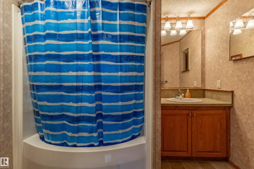 Bathroom featuring a white shower-tub combination, wood-finish vanity, integrated sink, and large mirror - 1529 Range Road 272 Rural Parkland County, Alberta, Rural Parkland County, AB - Indoor Photo Showing Other Room