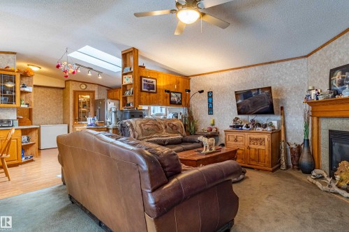 Expansive living area featuring a ceiling fan, a prominent skylight, and a built-in fireplace with a wood mantle - 1529 Range Road 272 Rural Parkland County, Alberta, Rural Parkland County, AB - Indoor Photo Showing Living Room With Fireplace