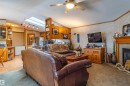 Expansive living area featuring a ceiling fan, a prominent skylight, and a built-in fireplace with a wood mantle - 1529 Range Road 272 Rural Parkland County, Alberta, Rural Parkland County, AB  - Indoor Photo Showing Living Room With Fireplace 