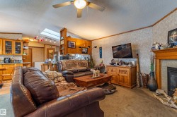Living area featuring a ceiling fan, a prominent fireplace with a wood mantel, and built-in shelving - 