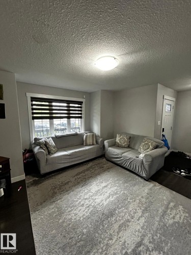 Spacious living area featuring dark wood-finish flooring and a large area rug - 1868 30 Street Nw, Edmonton, AB - Indoor