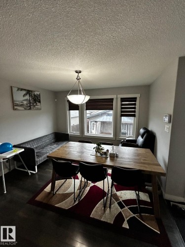 Dining area featuring dark wood-finish flooring, light grey walls, and a multi-light pendant fixture - 1868 30 Street Nw, Edmonton, AB - Indoor Photo Showing Dining Room
