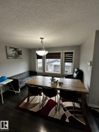 Dining area featuring dark wood-finish flooring, light grey walls, and a multi-light pendant fixture - 
