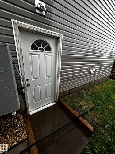 Side entry door with decorative fanlight and panel detailing, complemented by horizontal vinyl siding - 1868 30 Street Nw, Edmonton, AB - Outdoor With Exterior