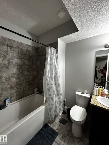 Bathroom featuring a tub and shower combination with stone-look tile surround - 1868 30 Street Nw, Edmonton, AB - Indoor Photo Showing Bathroom