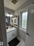 Compact bathroom featuring a single vanity with an oval sink, a light-toned countertop, and white cabinetry - 1868 30 Street Nw, Edmonton, AB  - Indoor Photo Showing Bathroom 