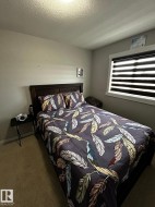 Carpeted flooring, window with horizontal blinds, wall-mounted light fixture, and dark wood-finish headboard - 