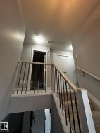 Carpeted staircase with light wood-finish railings and black metal balusters - 