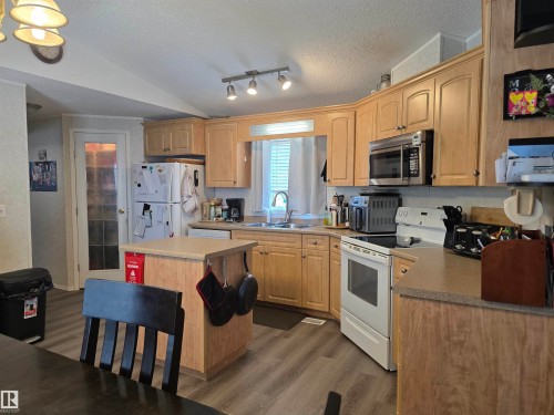 Kitchen featuring wood-finish cabinetry, track lighting, and a center island - 5012 53 Ave, Breton, AB 