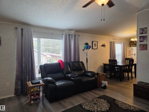 Open concept living space featuring wood-finish flooring, a ceiling fan, and a dining area with a dark wood table and chairs - 5012 53 Ave, Breton, AB 