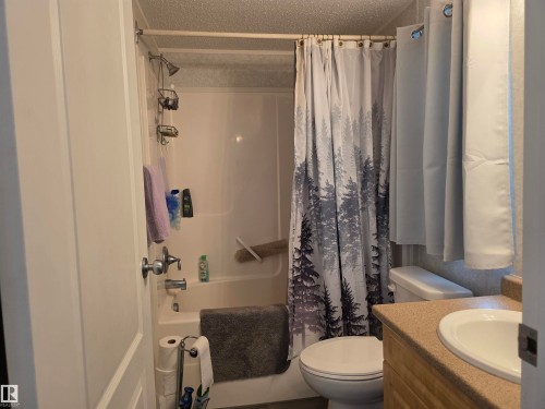 Full bathroom featuring a shower-tub combination, a vanity with an integrated sink, and a commode - 5012 53 Ave, Breton, AB 