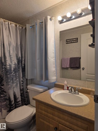 Bathroom featuring a vanity with a light-colored countertop, an undermount sink, and a chrome faucet - 5012 53 Ave, Breton, AB 