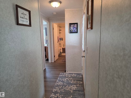 Hallway featuring wood-finish flooring, light-colored walls, and a ceiling-mounted flush light fixture - 5012 53 Ave, Breton, AB 
