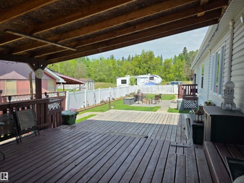 Expansive covered deck featuring wood-finish flooring and an open-beam ceiling - 5012 53 Ave, Breton, AB 