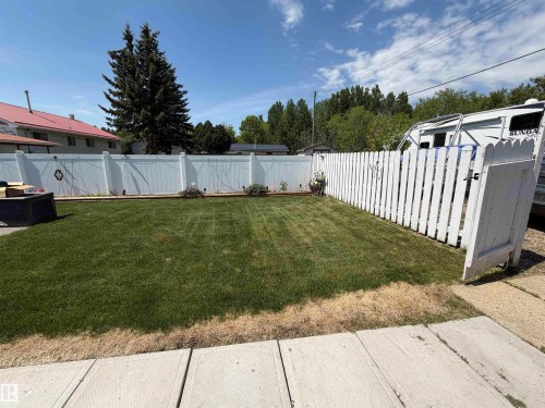Expansive green lawn framed by a white privacy fence and a white picket fence - 5012 53 Ave, Breton, AB 